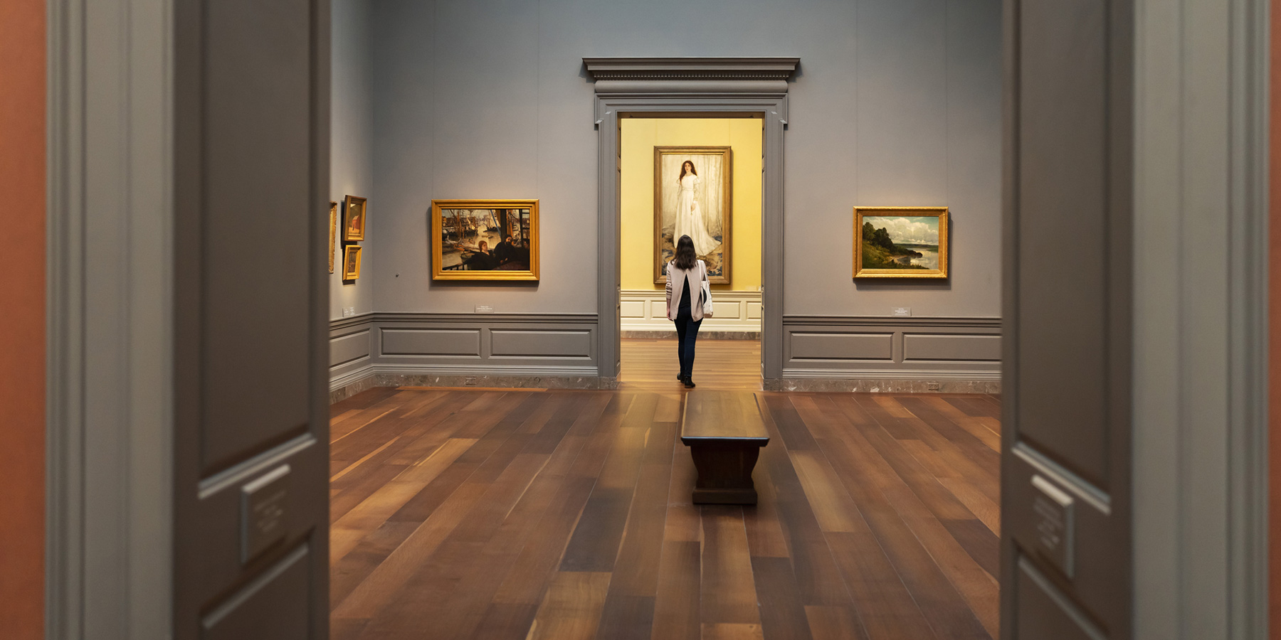 View through a doorway of a visitor studying "Symphony in White, No. 1: The White Girl" (1943.6.2) by James McNeill Whistler.  Keywords